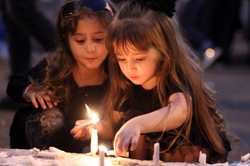 Iraqi girls light candles on Saturday at the site of a suicide-bombing attack which took place on July 3 in Baghdad's Karrada neighbourhood. The Baghdad bombing claimed by the Daesh group killed 292 people, according to a new toll issued on Thursday, many of whom were trapped in blazing buildings and burned alive (AFP photo)