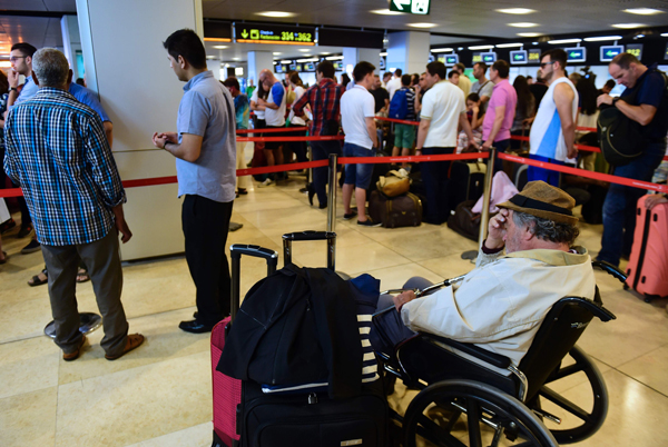 People wait at Turkish Airlines desk at Adolfo Suarez airport in Barajas, near Madrid, on Saturday as Turkish Airlines cancelled their flights following last night's attempted coup in Turkey (AFP photo)
