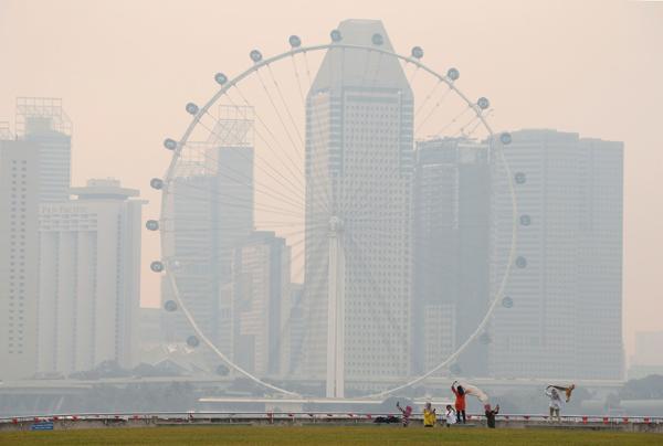 People take photos near the Singapore Flyer observatory wheel shrouded by haze, on Friday (Reuters photo)
