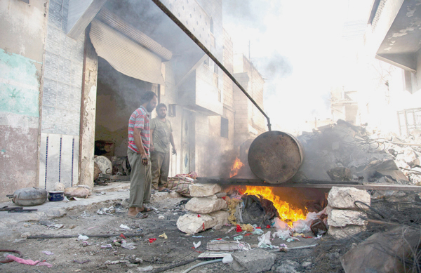 Syrian Mohammed Ibrahim (left) and Abu Majd distil melted plastic in a barrel as part of a refining process to produce fuel on September 10, 2016, in Aleppo's rebel-held eastern district of Sakhur (AFP photo)