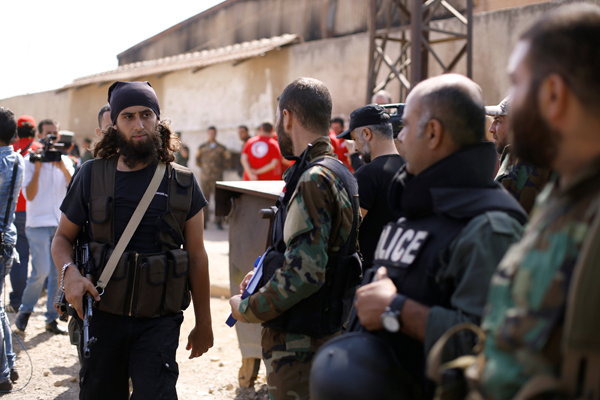 A rebel fighter (left) walks next to Syrian army soldiers prior to evacuating the besieged Waer district in the central Syrian city of Homs, after a local agreement reached between rebels and Syria's army, Syria, Thursday (Reuters photo)
