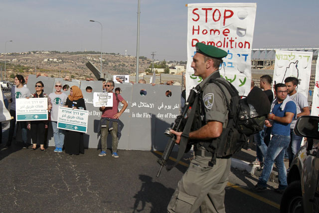 Israeli forces stand guard during a demonstration of Israeli and Palestinian members of the ‘Combatants For Peace’ association on Friday on a road close to the West Bank village of Al Khader, near the biblical town of Bethlehem, to protest against the demolition of Palestinian houses in the West Bank by Israeli authorities who say they are built without permission (AFP photo)