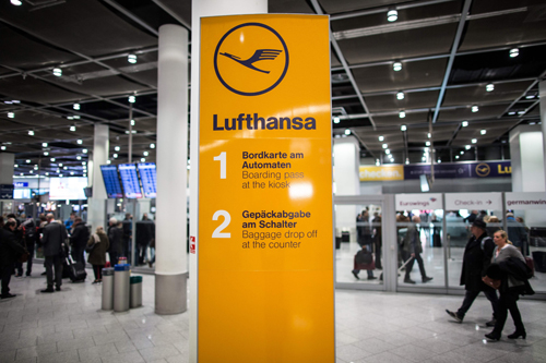Flight passengers walk past an information sign with the logo of German airline Lufthansa on Friday at the airport in Duesseldorf, western Germany (AFP photo)