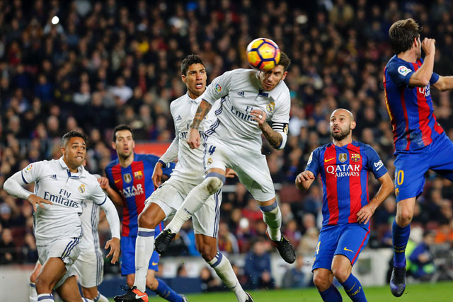 Real Madrid’s defender Sergio Ramos (centre) heads a ball to score the equaliser past Real Madrid’s French defender Raphael Varane (3rd left) and Barcelona’s Argentinian defender Javier Mascherano (right) during the Spanish league football match at the Camp Nou Stadium in Barcelona on Saturday  (AFP photo by Pau Barrena)