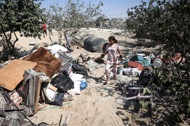 A Palestinian youth stands near belongings at the site of Israeli strikes on a makeshift displacement camp in Mawasi in Khan Yunis in the southern Gaza Strip on Tuesday (AFP photo)