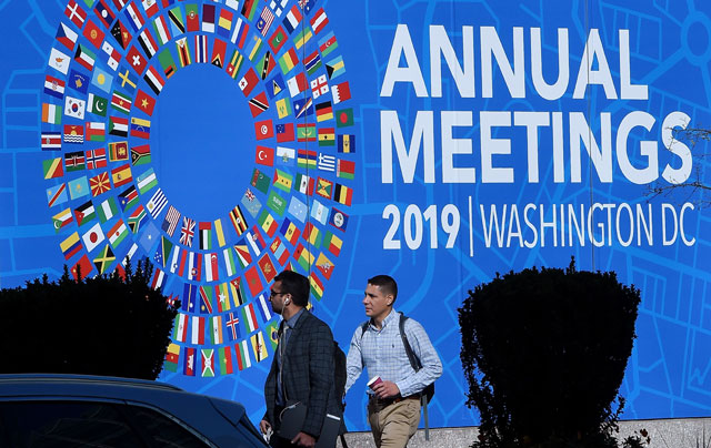 People pass in front of the IMF building during the IMF and World Bank Fall Meetings on Tuesday in Washington, DC (AFP photo)