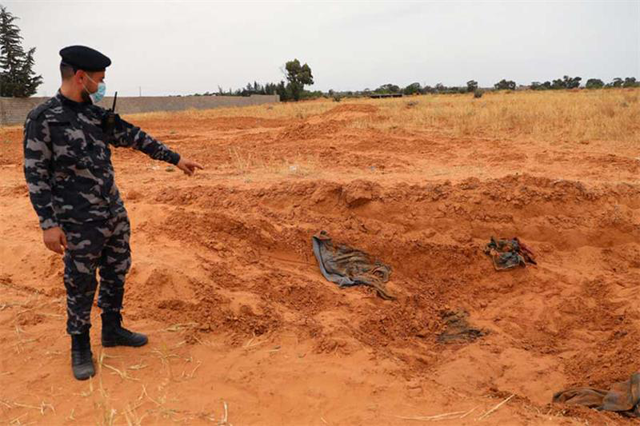 A member of security forces affiliated with the GNA's Interior Ministry surveyed the reported site of a mass grave in the town of Tarhuna, southeast of the capital Tripoli, Libya. (AFP file photo)