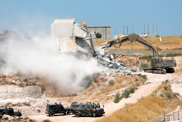 This photo taken from occupied Jerusalem on Monday shows Israeli forces tearing down one of the Palestinian buildings still under construction in the West Bank village of Dar Salah, adjacent to the Sur Baher area, which straddles the occupied West Bank and Jerusalem (AFP photo)