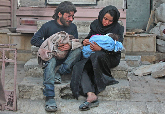 A Syrian man and a woman mourn over the body of one of their children (right) in the rebel-held besieged town of Douma following air strikes on the eastern Ghouta region on the outskirts of the capital Damascus on Wednesday (AFP photo)