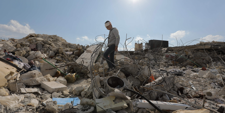 A Syrian boy, who lost his family and was also wounded as a result of the deadly earthquake hit Turkey and Syria, walks amid the rubble of his family home in the town of Jindayris, in the rebel-held part of Syria's Aleppo province, on Saturday (AFP photo)