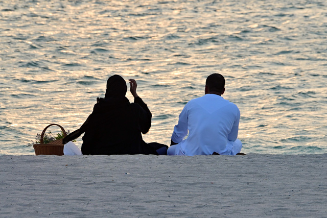 A couple watches the sunset at the beach near Bur Al Arab in the Gulf Emirate of Dubai on Wednesday (AFP photo)