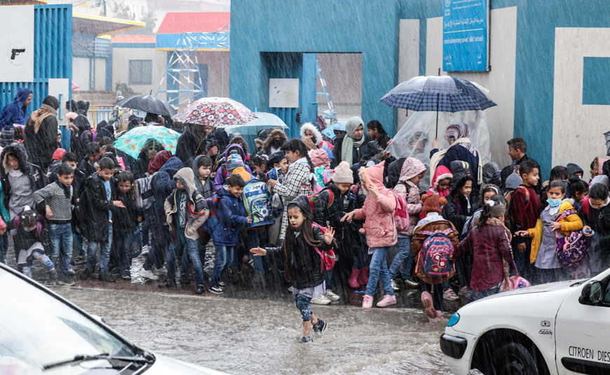 Palestinian UNRWA school pupils wait to cross a flooded street in heavy rain in Gaza City, on Saturday (AFP photo)