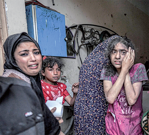 A woman and children react following Israeli bombardment in Nuseirat in the central Gaza Strip on Monday, amid the ongoing Israeli aggression (AFP photo)