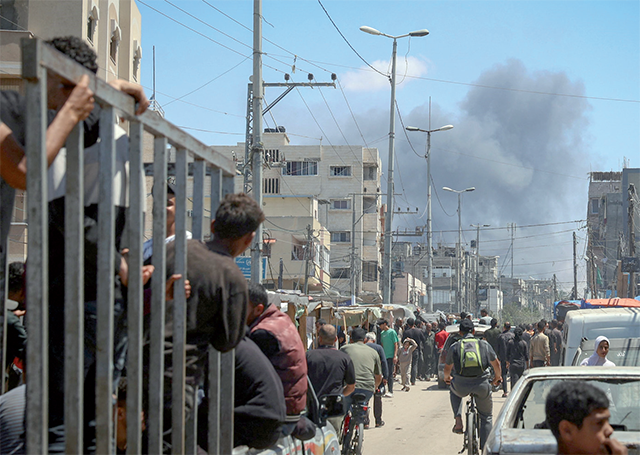 Palestinians crowd a street as smoke billows nearby from Israeli strikes in Rafah in the southern Gaza Strip on Tuesday (AFP photo)