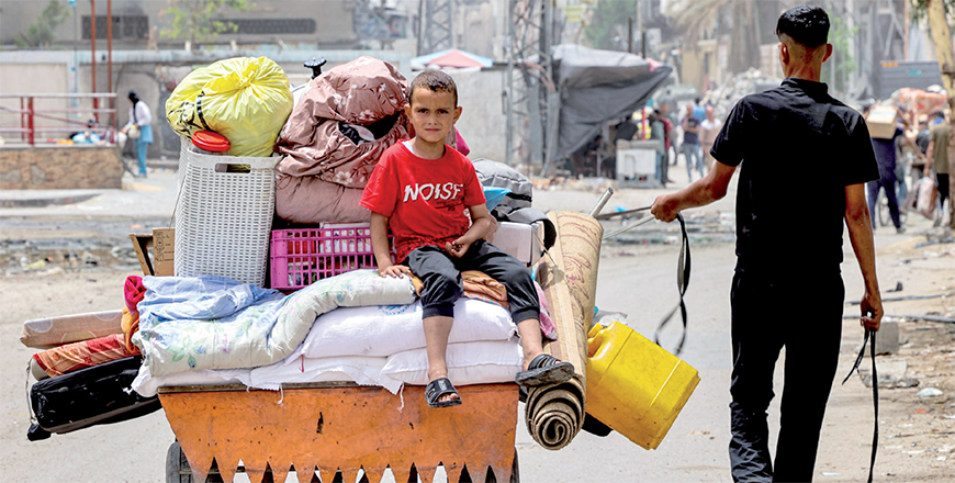 A boy looks on as he sits atop cushions and mattresses loaded in the back of an animal-drawn cart led by a man as they evacuate from Sheikh Zayed in the northern Gaza Strip on May 11, 2024 (AFP photo)