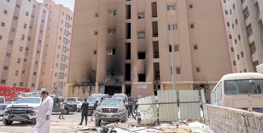 People walk past a building which was engulfed by fire, in Kuwait City, on Wednesday (AFP photo)