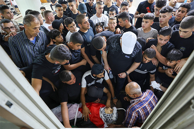 Relatives mourn over the body of 14-year-old Palestinian Fares Abu Samrah, who was killed by Israeli forces during an overnight raid, during his funeral in Qalqilya in the occupied West Bank, on Thursday (AFP photo)