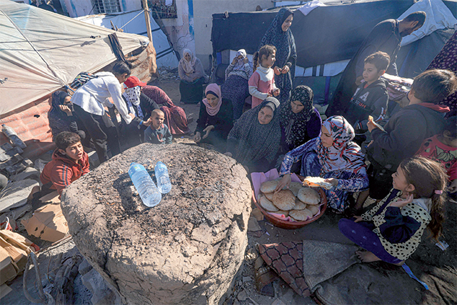 Displaced Palestinians bake bread in Deir Al Balah, in the central Gaza Strip, on Tursday, on the seventh day of a truce between Israel and Hamas (AFP photo)