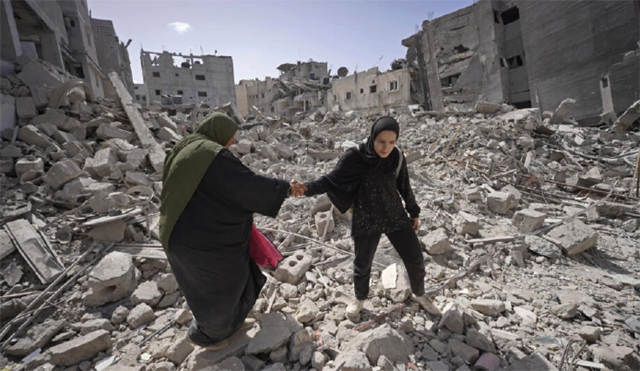 Palestinians walk trough the rubble of houses destroyed by Israeli bombardment of Khan Yunis (AFP photo)