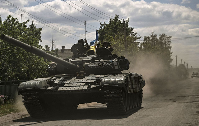 Ukrainian troops members move towards the front line with an army's Main Battle Tank in the eastern Ukrainian region of Donbas on Tuesday (AFP photo)