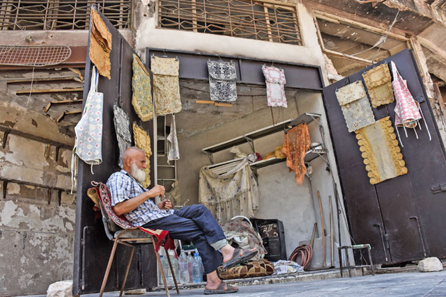 This photo taken on July 22 shows 62-year-old Mohammad Shawash sitting outside his textile shop amid the destruction in the old city of Aleppo (AFP photo)