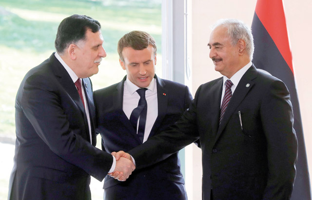 French President Emmanuel Macron (centre) looks on as Libyan Prime Minister Fayez Al Serraj (left) shakes hands with General Khalifa Haftar, commander in the Libyan National Army, after talks aimed at easing tensions in Libya, in La Celle-Saint-Cloud, near Paris, on Tuesday (AFP photo)