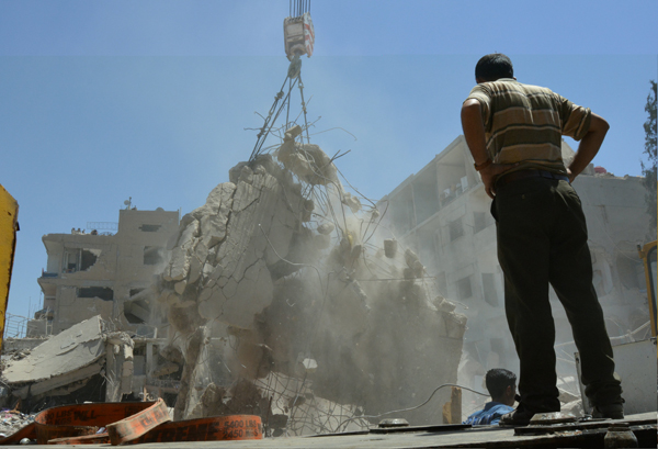 A man watches as debris is removed during a search for survivors at a damaged site after two bomb blasts claimed by the Daesh terror group hit the northeastern Syrian city of Qamishli near the Turkish border, on Wednesday (Reuters photo)