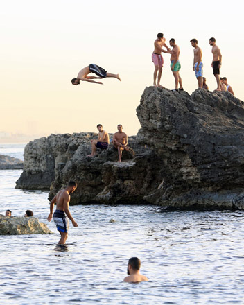 Libyan youth cool off by diving off rocks in the seaside during sunset in the capital Tripoli on Thursday (AFP photo)