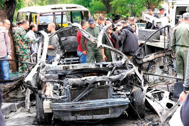 Syrians surround the wreckage of a car following an explosion in Damascus on Wednesday (AFP photo)