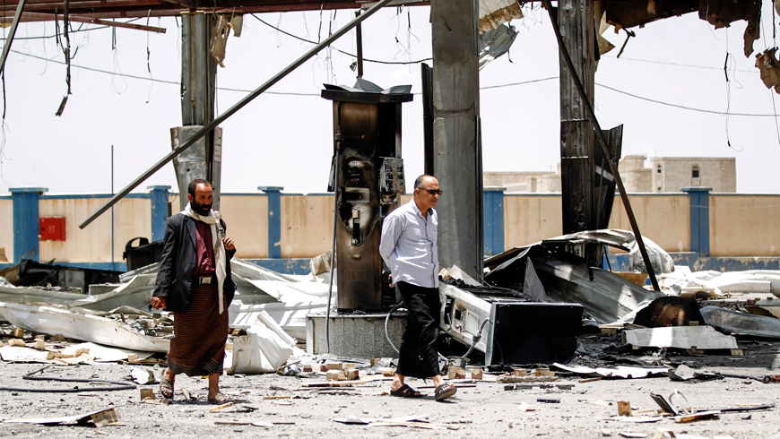 Yemeni men walk through the rubble and debris of a destroyed petrol station that was hit by an air strike in the capital Sanaa on Sunday (AFP photo)