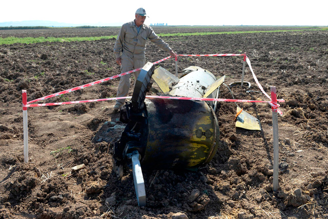 A man stands by what is said is the remains of a Tochka U missile in a field in Fizuli district, Azerbaijan, on Sunday, during the ongoing military conflict between Armenia and Azerbaijan over the breakaway region of Nagorno-Karabakh (AFP photo)