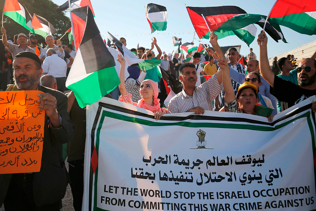 Palestinians wave their national flag as they demonstrate in support of bedouin inhabitants near their village of Khan Al Ahmar, in the occupied West Bank, on Wednesday (AFP photo)