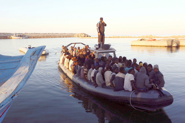 African migrants are seen seated in a boat, after being rescued by the Libyan navy following their boat suffering engine failure, near the coastal town of Gharaboli, east of Tripoli, Libya, on November 20, 2014 (Reuters photo)