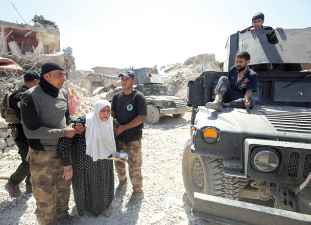 Members of the Iraqi anti-terrorism forces help an elderly woman as they advance through the Old City of Mosul on Wednesday, during the ongoing offensive to retake the last district still held by the Daesh militants (AFP photo)