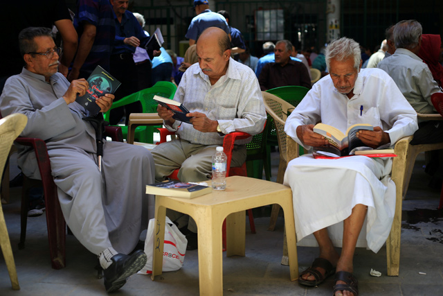 Iraqi men read books at a coffee shop in Mutanabbi Street in Baghdad, on June 22 (Reutres photo)