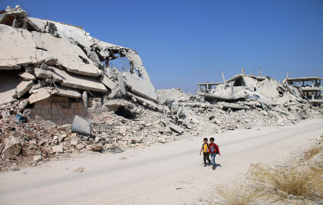 In this file photo taken on September 17, 2017, Syrian schoolchildren walk past destroyed buildings in a rebel-held area of the southern city of Daraa (AFP photo)