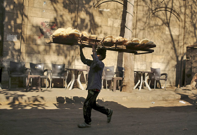 A bakery worker carries freshly baked bread on his head to deliver it to shops in Cairo, Egypt, on February 14, 2016 (Reuters photo)
