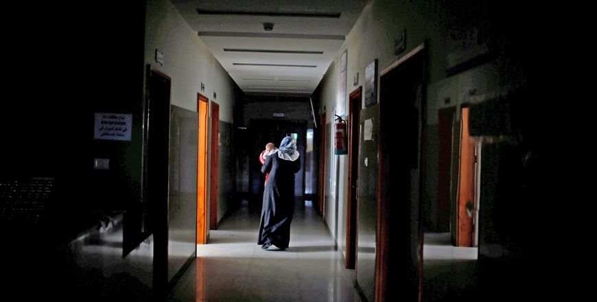 A Palestinian woman carries her sick child as she walks through the corridor at Durra hospital in Gaza city on Tuesday. So far generators have stopped at three of Gaza's 13 hospitals and 14 of its 54 medical centres, and fuel for emergency generators will run out within 10 days, the UN said on Tuesday (Reuters photo)