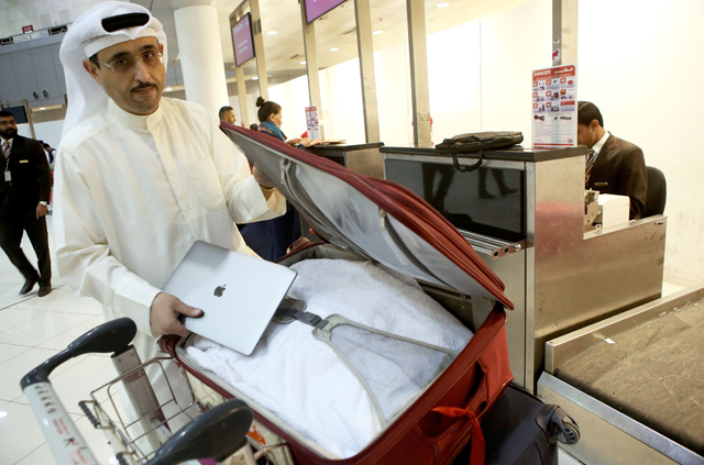 Kuwaiti social media activist Thamer Al Dakheel Bourashed puts his laptop inside his suitcase at Kuwait International Airport in Kuwait City before boarding a flight to the United States on Thursday (AFP photo)