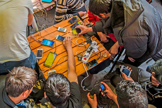 Migrants charge their mobile phones in a restaurant near the central bus station in Belgrade on March 24 (AFP photo)