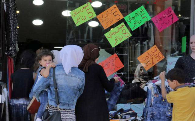 Customers check out offers at a clothing store in downtown Amman on Tuesday (Photo by Osama Aqarbeh)