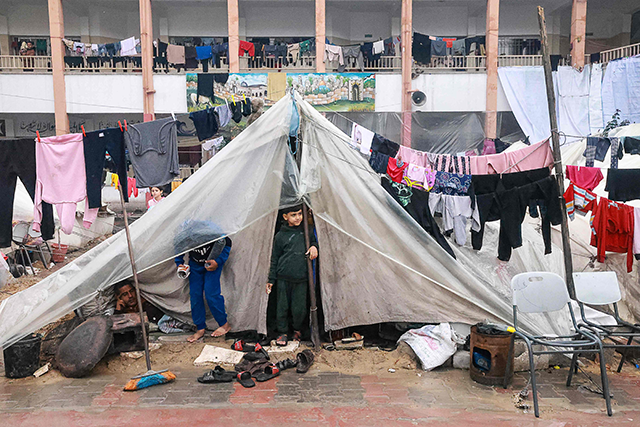 Palestinian boys stand in their makeshift tent at a camp set up on a schoolyard in Rafah in the southern Gaza Strip where most civilians have taken refuge, on Wednesday, as Israel continues with its war against the besieged enclave  (AFP photo)