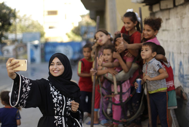 Palestinian Fatma Abu Musabah, 21, uses her mobile phone to take photos of children for her social media account in Deir Al Balah in the central Gaza strip on September 17 (AFP photo)
