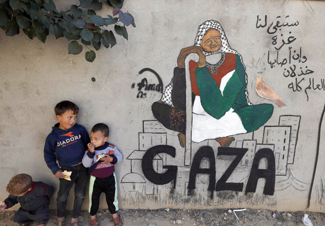 Displaced Palestinian children stand next to a mural painting by artist Amal Abo in Rafah in the southern of Gaza Strip, on Sunday (AFP photo)