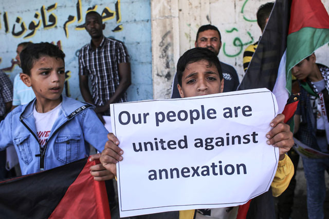 A young Palestinian holds a placard as he takes part in a protest against Israel's plans to annex parts of the occupied West Bank, in Rafah in the southern Gaza Strip, on Saturday  (AFP photo)