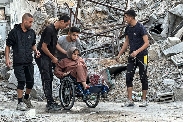 Palestinians use a wheelchair to transport through the rubble a woman who lost her leg when her family home was hit in an Israeli strike in the Jabalia refugee camp in the northern Gaza Strip, on November 7, 2024 (AFP photo)