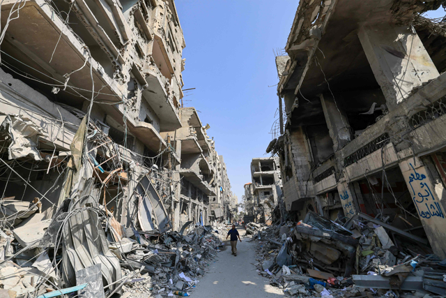 A Palestinian man walks amid the rubble of buildings hit in Israeli air strikes in Khan Yunis in the southern Gaza Strip on Tuesday (AFP photo)