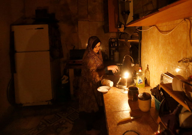 A Palestinian woman washes up in her kitchen during power cut at Shati refugee camp in Gaza City on Tuesday (Reuters photo)