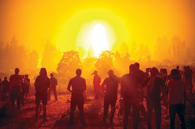 Local youths and volunteers gather in an open field and wait to support firefighters during a wildfire next to the village of Kamatriades, near Istiaia, northern Evia (Euboea) Island, on Monday (AFP photo)
