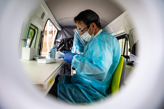 A medical worker handles a sample during a practice run of antigen testing for the COVID-19 coronavirus at a park near Kabukicho in Tokyo's Shinjuku district on Monday (AFP photo)